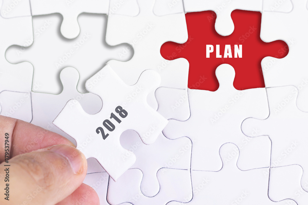 Business Concept - Female hand and missing puzzle with 2018 PLAN. Business Concept - Female hand and missing puzzle with 2018 PLAN.