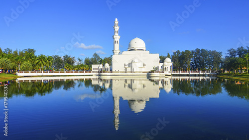 Mirror reflection of beautiful white floating mosque in a lake during blue sky. photo