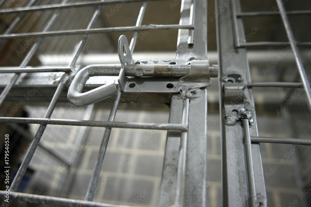 Unlocked gate of a metal storage cage with wire netting