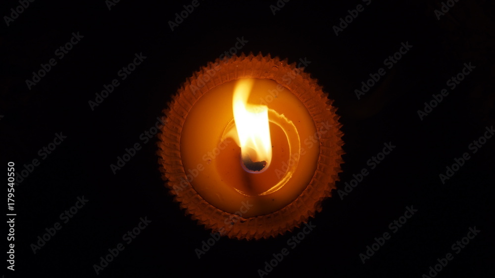 Fototapeta premium burning flat candle at night isolated on dark background