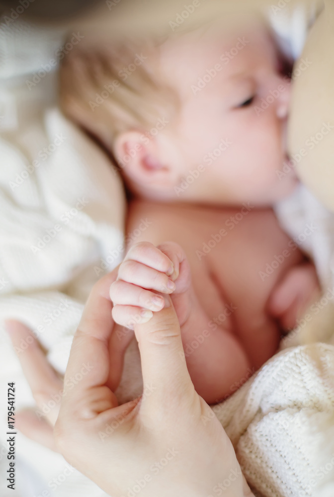 The newborn holds Mom's hand while breast feeding The newborn holds Mom's hand while breast feeding