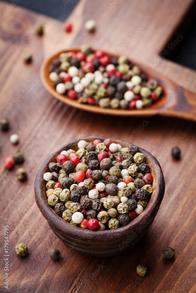 Peppercorns whole in rustic bowl on wooden board. Macro shot. Peppercorns whole in rustic bowl on wooden board. Macro shot.
