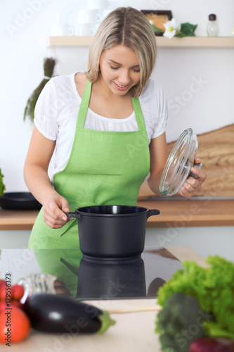 Woman cooking soup in kitchen. Healthy meal and culinary concept