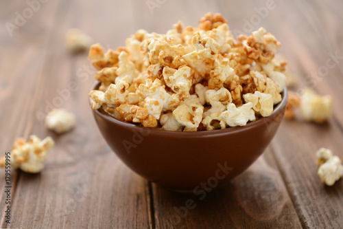 Bowl with tasty caramel popcorn on wooden background