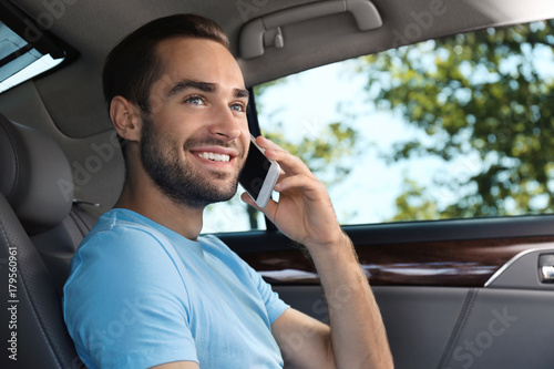 Handsome young man talking on mobile phone in car