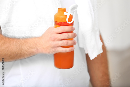 Young man holding bottle with protein shake, closeup