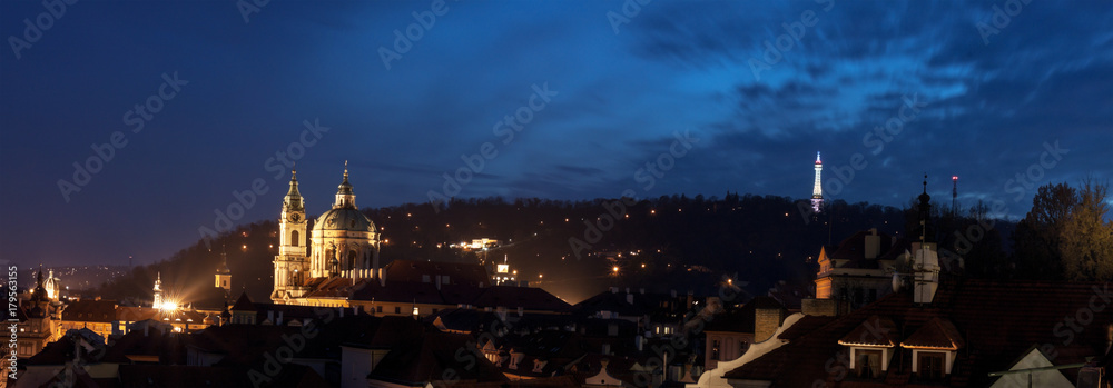 Lesser Quarter after Dark. With Petrin hill with lookout tower and St Nicholas Cathedral dome and clock tower. Old district of Prague after sunset during blue hour.