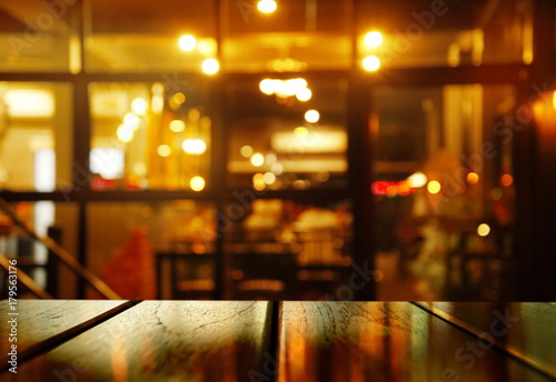 top of wood table with blur orange light party in pub or bar background
