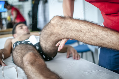 fisioterapista ortopedico massaggia la gamba di un giovane sportivo per sciogliere la muscolatura