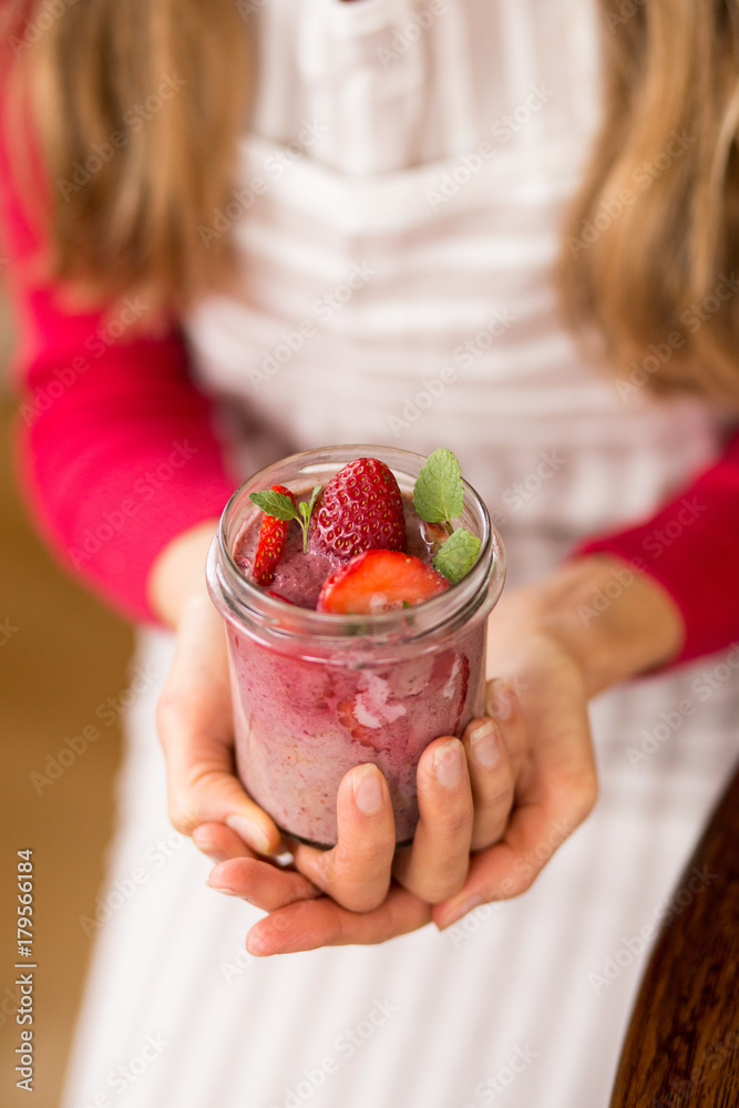 Fruit dessert with strawberries in the jar, in the hands of the cook's girlfriend
