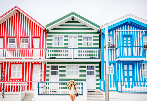 Old houses painted in colorful stripes with woman in swimsuit during the summer vacation in Costa Nova resort in Portugal