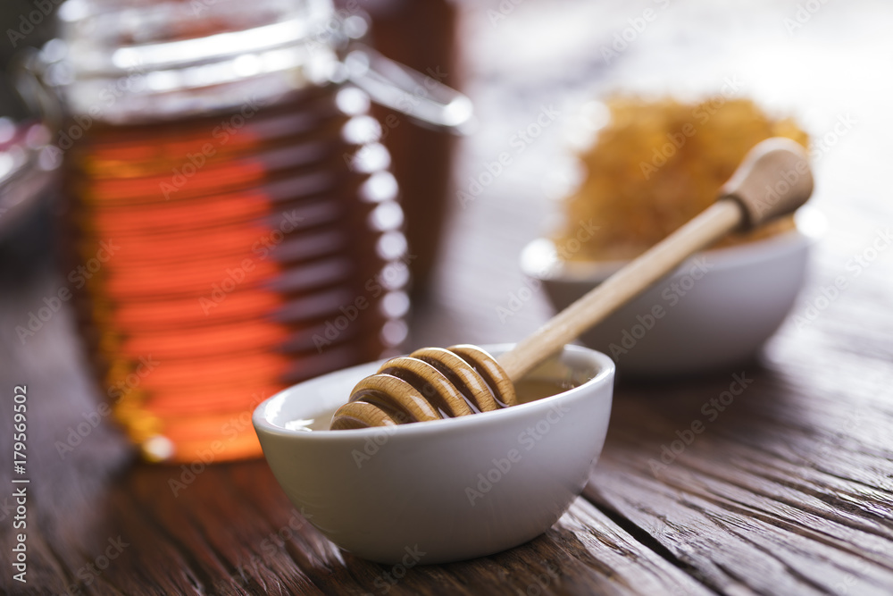 Honey in jar with honey dipper on wooden background Honey in jar with honey dipper on wooden background