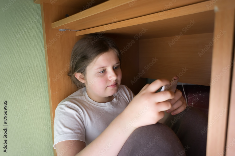 the upset girl is under the table hiding from the problems with her mobile phote. escape from the problems in virtual computer world and games the upset girl is under the table hiding from the problems with her mobile phote. escape from the problems in virtual computer world and games