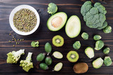 Assorted green vegetables,  avocado, kiwi, feijoa, broccoli and Brussels sprouts on wooden table. Healthy food concept, flat lay
