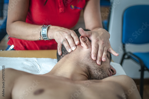 fisioterapista massaggia giovane paziente per curare un dolore cervicale
 photo