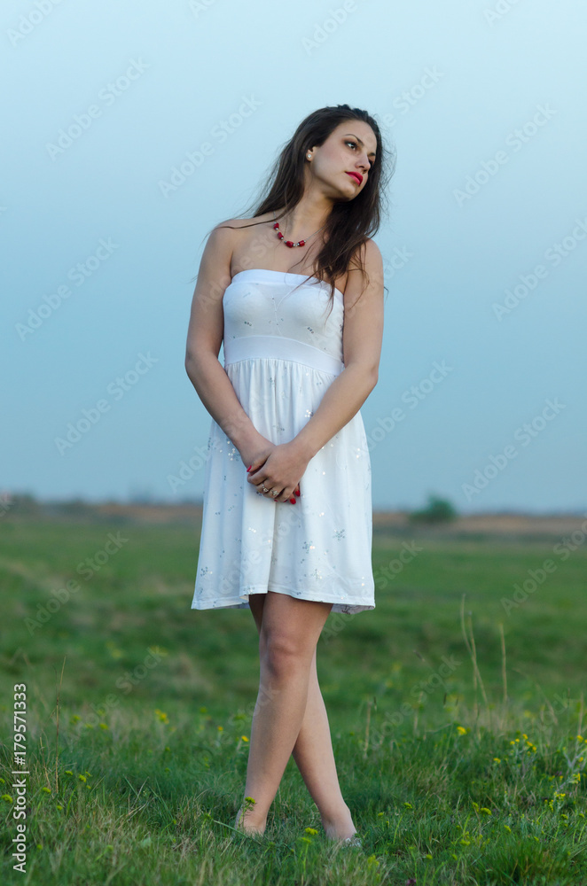 Beautiful woman in white dress walking on summer meadow Beautiful woman in white dress walking on summer meadow