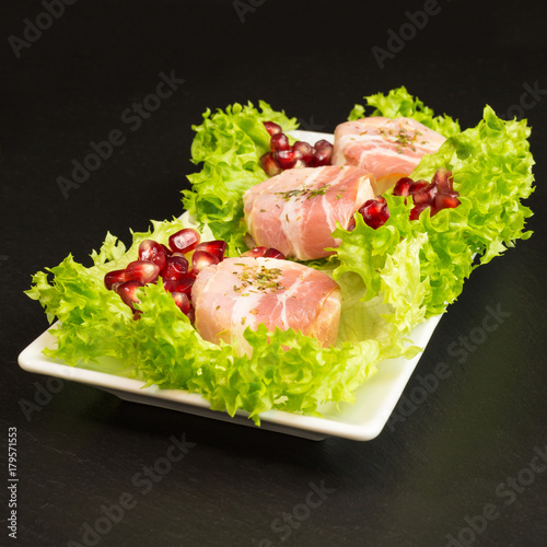 goat cheese with bacon on a frisee lettuce leaf with pomegranate as garnishing