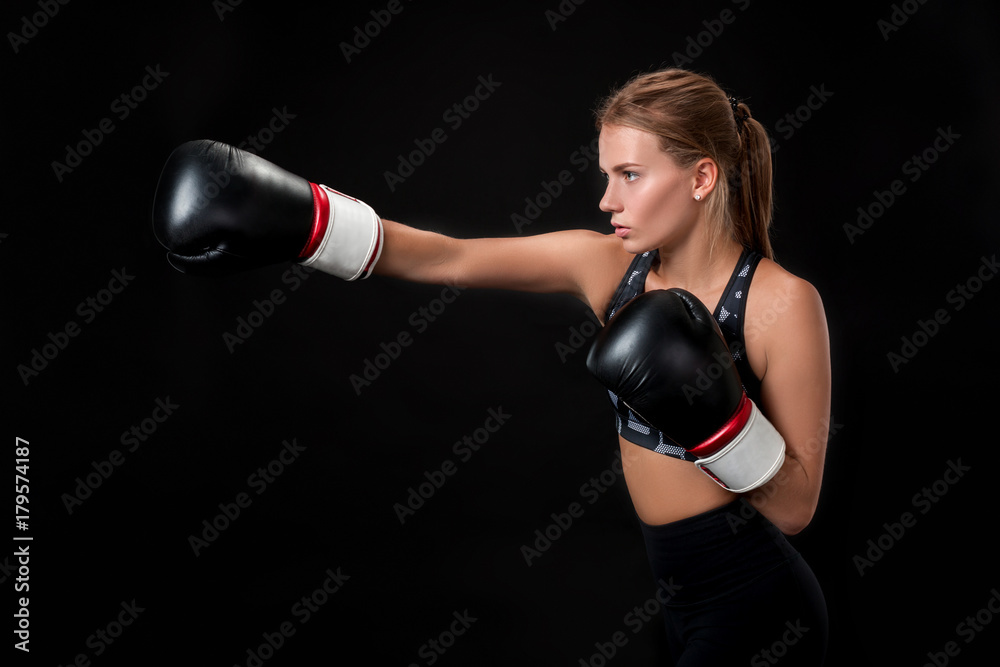Beautiful female athlete in boxing gloves, in the studio on a black background.