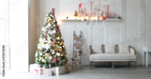 4K video footage of white room with Christmas and New Year interior decoration. Green tree decorated with toys and flashing garland