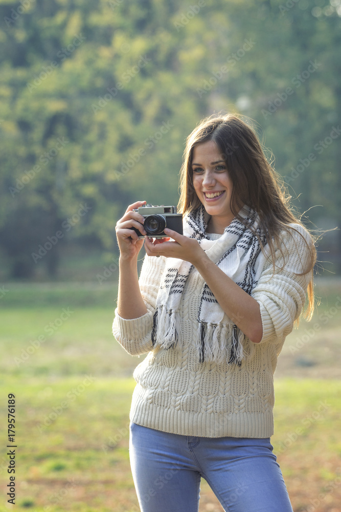 Long hair beautiful girl with old carema taking photo in park and smile