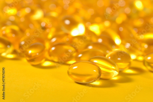 Omega-3 fish fat oil capsules close up on a yellow background.