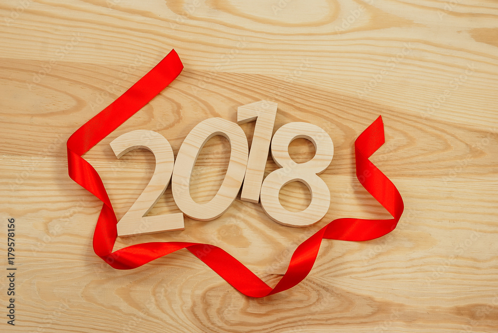 Wooden figures forming 2018, carved from light wood on the background of old wood. Tie the red ribbon. New Year Idea, postcard, poster, greetings. Wooden figures forming 2018, carved from light wood on the background of old wood. Tie the red ribbon. New Year Idea, postcard, poster, greetings.