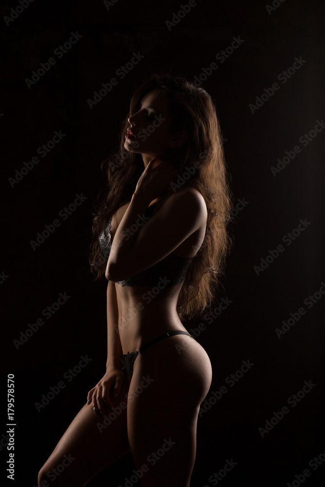 Silhouette of seductive slim model in black lingerie at studio