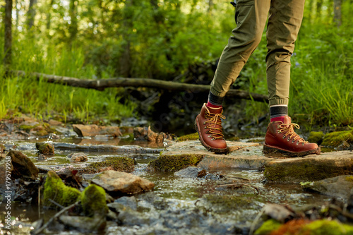 Female hiker in leather boots crossing a stream