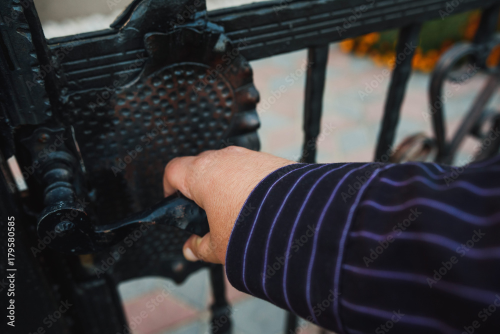 Fototapeta premium Fence. Hand opening metal fence gate.