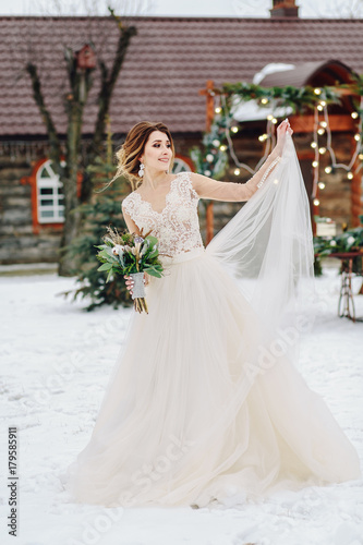Gorgeous girl in white wedding dress walking in winter park.