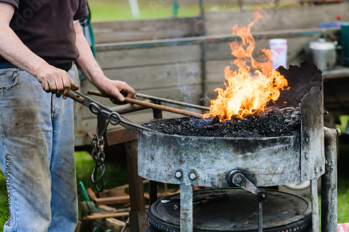 Blacksmith heats up some iron bars in a forge