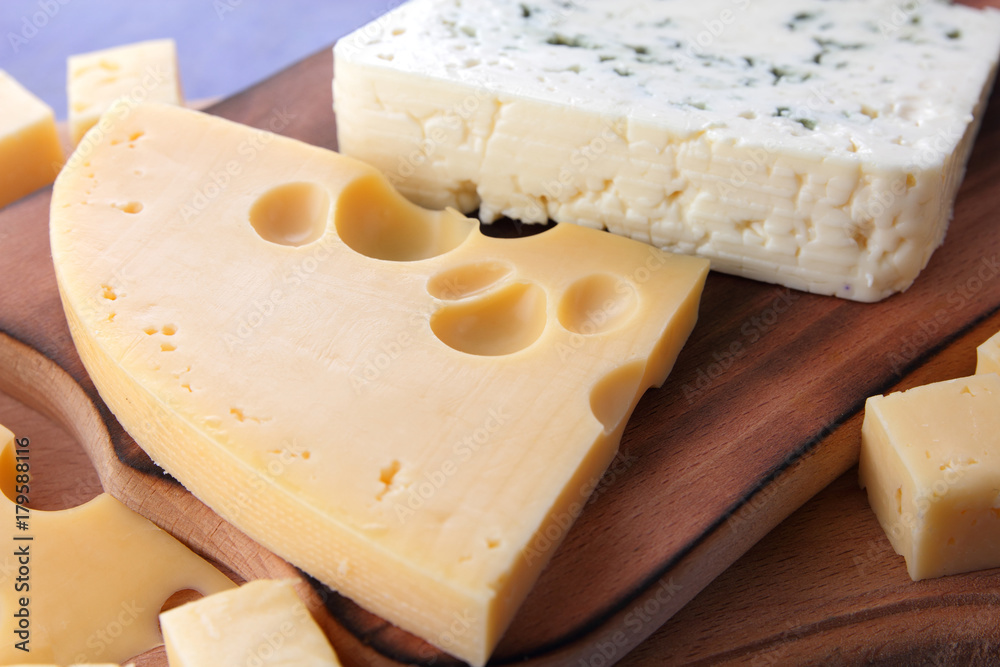 Yellow cheese, hard cheese with holes, Polish cheese, cheese with a mold on a wooden board, different cheeses on a dark blue background in a minimalist style, retro style