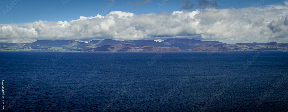 Vue panoramique dans le comté de l'anneau du Kerry. Un bras de mer, avec au fond des collines ensoleillées et ruban de nuages 