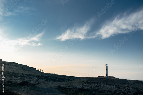Silhouette of a couple on a mountain with a lighthouse