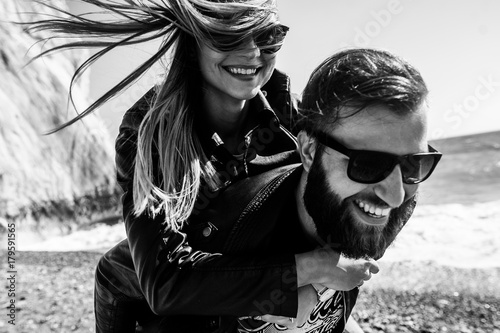 Black&white photo of happy couple in the leather jackets running on the beach photo