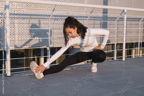 Fitness girl stretching leg on outdoor photo