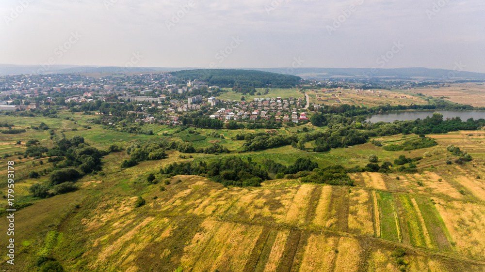 Fototapeta premium Aerial view of the summer countryside. A flight over a green field and town