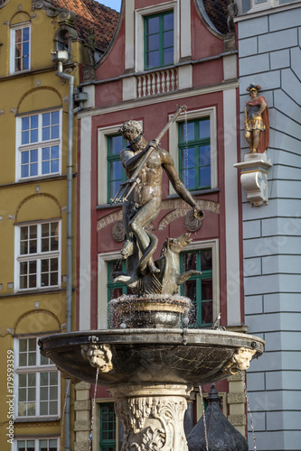 Historic Neptune Fountain, located at Long Market Street (Long Lane), in front of old buildings at the Main Town (Old Town) in Gdansk, Poland, on a sunny day.