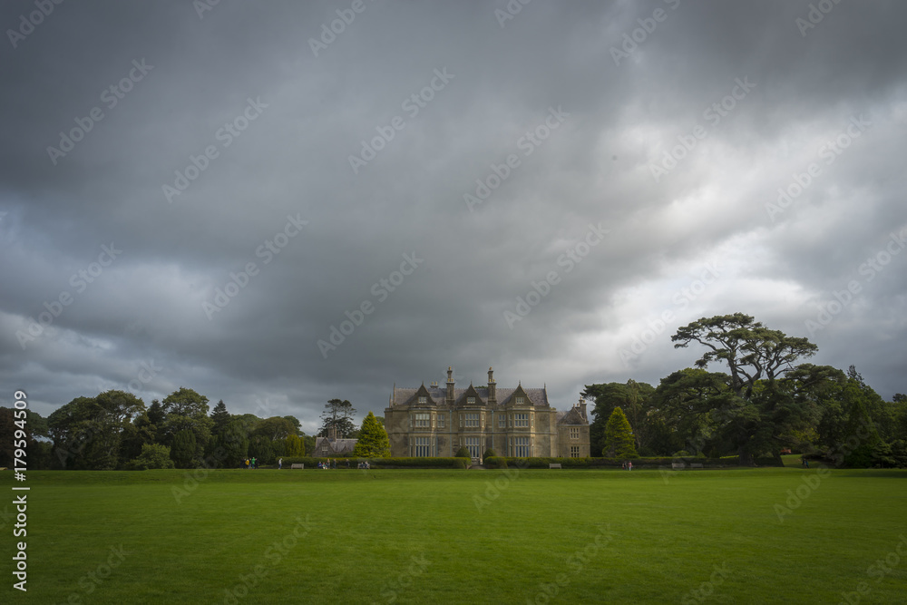 Vue dans le parc du château de Muckross House, sous un ciel chargé, mais ensoleillé.