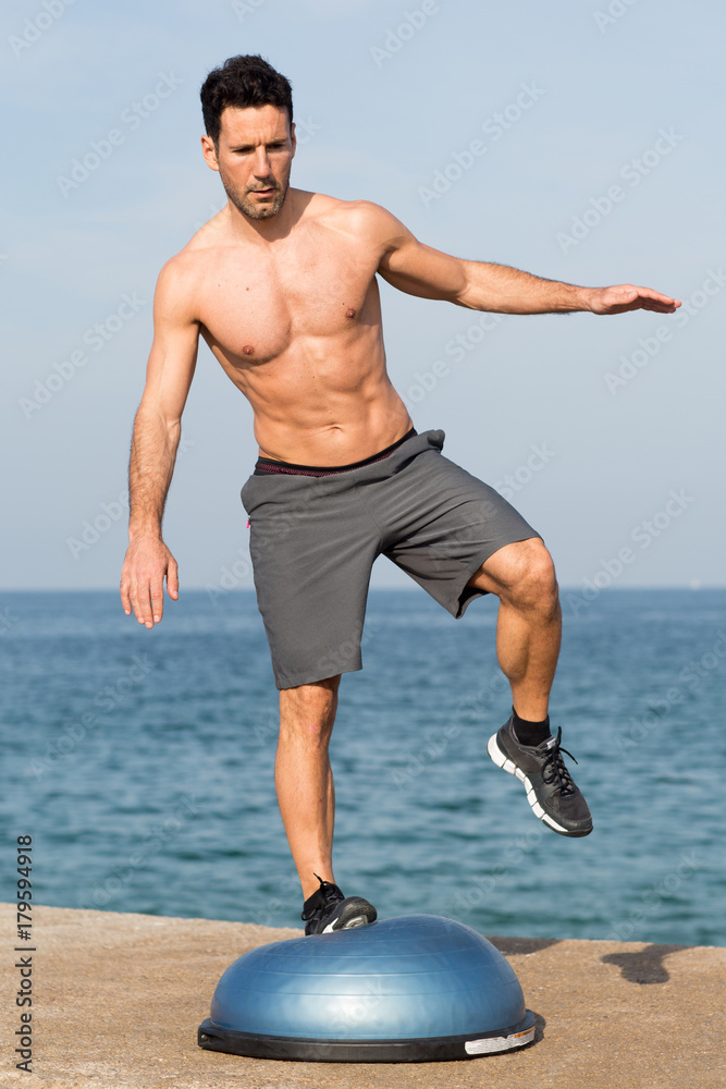 Athletic man balancing with one leg on bosu balance platform by the sea  Stock Photo | Adobe Stock