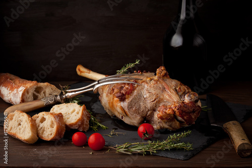 Freshly roasted lamb leg with herbs and bottle of red wine