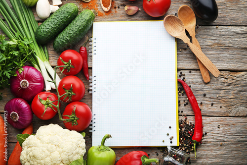 Blank recipe book with vegetables on wooden table photo