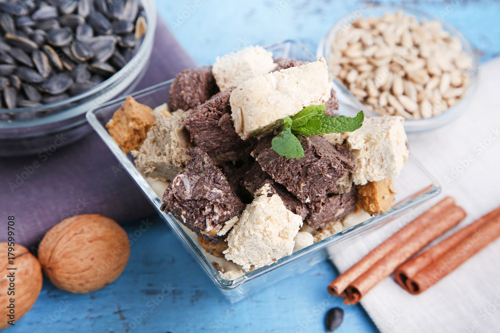 Fototapeta premium Tasty slices of halva in bowl on wooden table