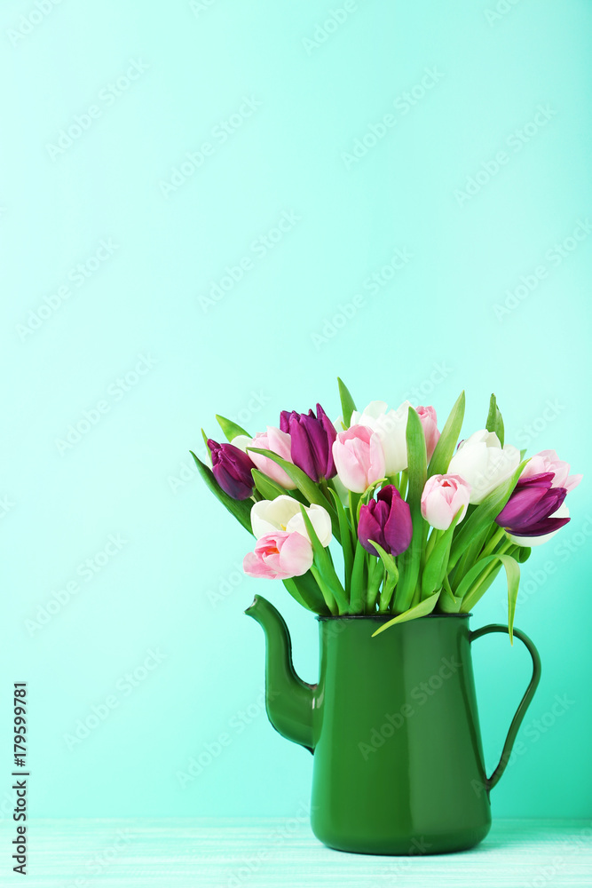 Bouquet of tulips in jug on green background