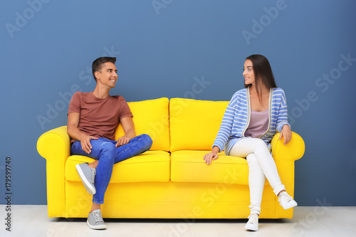 Young couple sitting on yel...