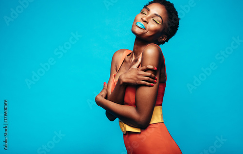 Woman with vivid makeup hugging herself