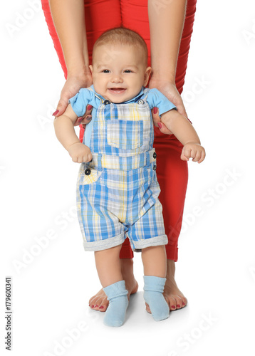 Young woman teaching her cute baby to walk, on white background