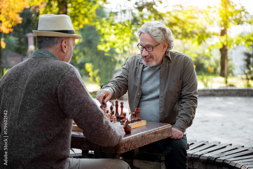 Cheerful senior men playing chess together outdoor Cheerful senior men playing chess together outdoor