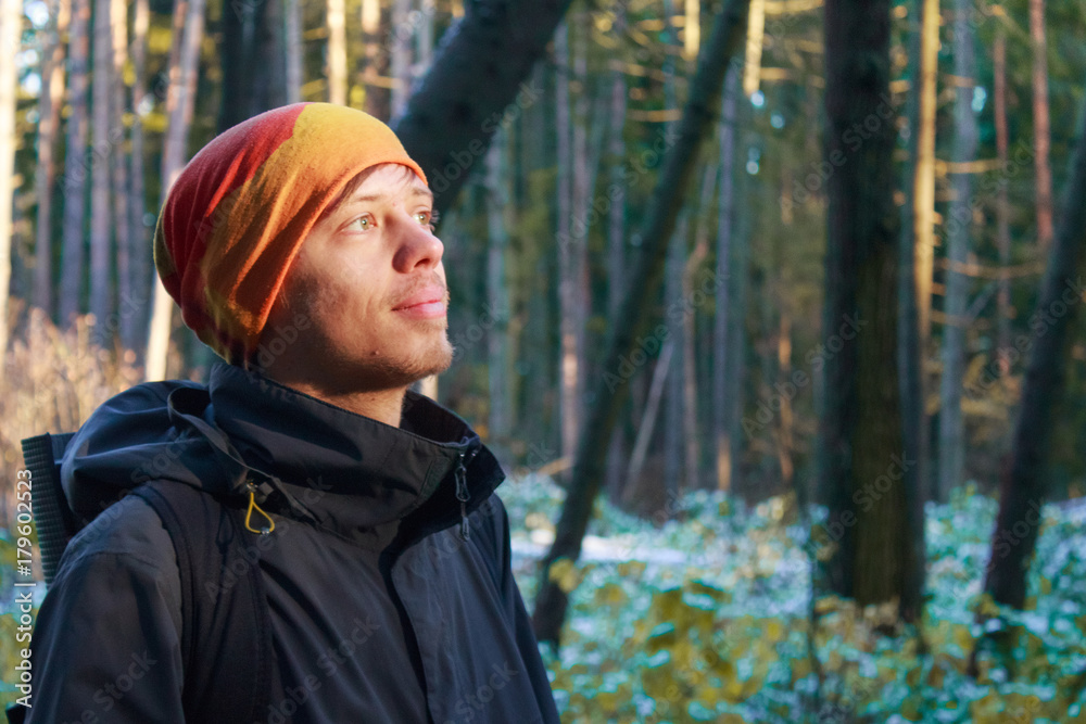 Man hiking in forest. Close-up of a young man in warm clothing looking up in morning forest Man hiking in forest. Close-up of a young man in warm clothing looking up in morning forest