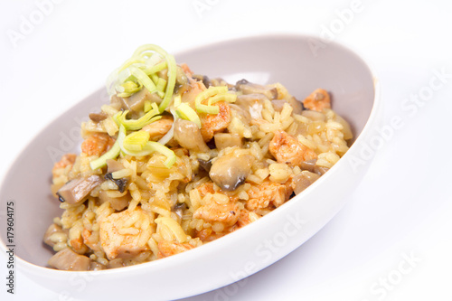 Risotto with mushrooms and chicken decorated with leek on a white background